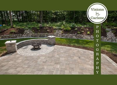 Stone paver patio with fire pit and curved seating wall surrounded by garden