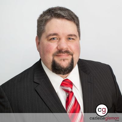 Professional business headshot of a man in a dark pinstripe suit