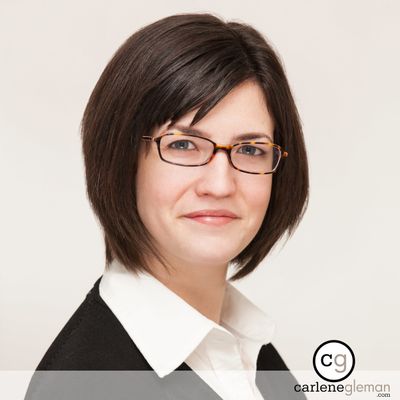 Professional business headshot of a woman with dark hair and glasses