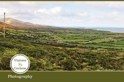 Panoramic landscape of County Kerry, Ireland with rolling green fields, mountains, and ocean