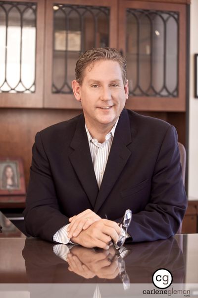 Executive portrait of a man seated at a conference table in a wood-paneled office
