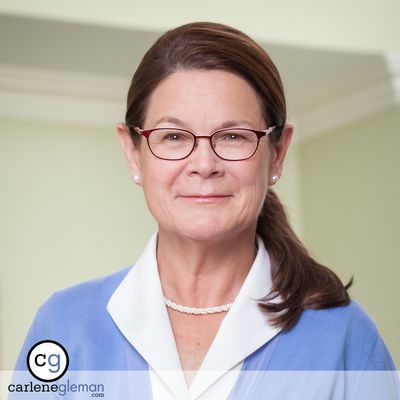 Executive portrait of a woman in a blue blazer with glasses and pearl necklace