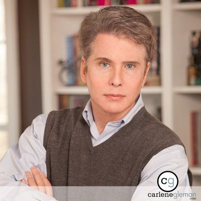 Executive portrait of a man with arms crossed in front of a bookshelf
