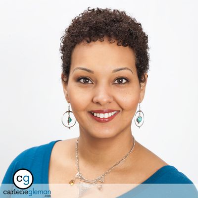 Professional business headshot of a woman with natural hair in a teal top